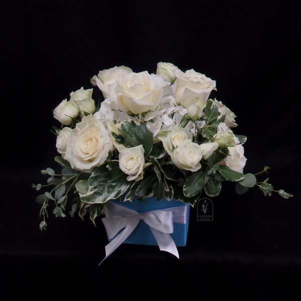 White roses arranged in a blue box with a white ribbon