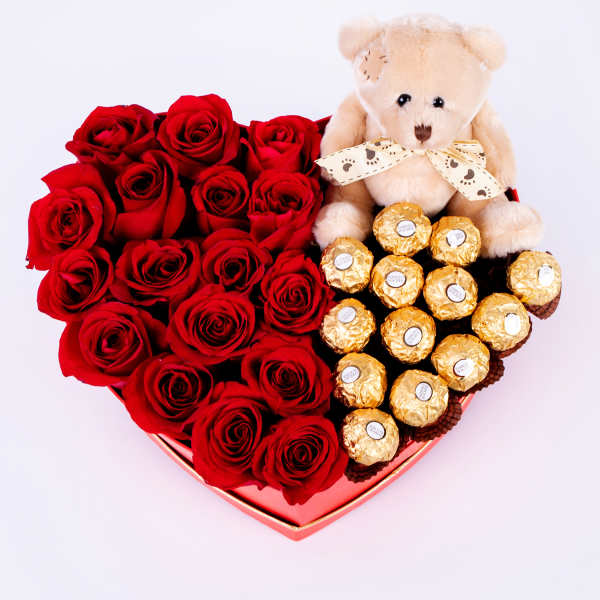 Heart-shaped box of red roses with a teddy bear and chocolates