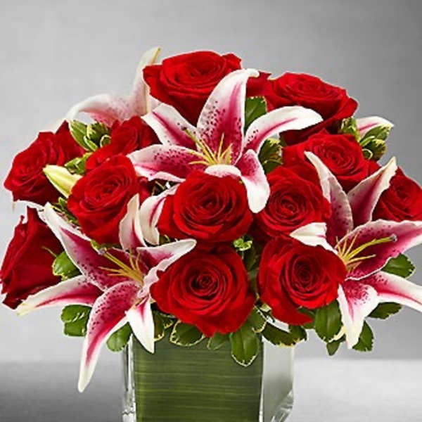 Red roses and pink lilies arranged in a square glass vase