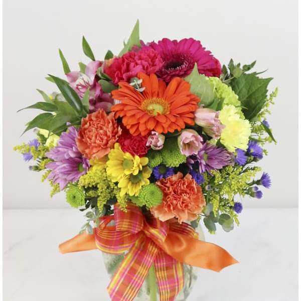 Colorful mixed flower bouquet in a glass vase with ribbon