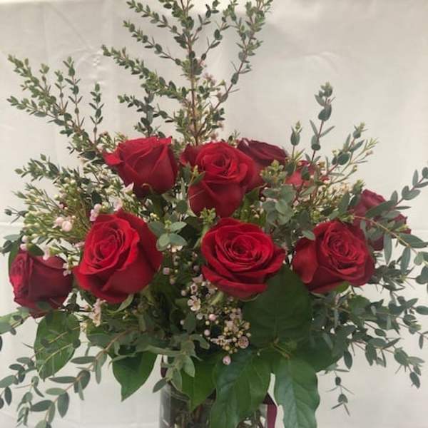 Red roses arranged in a clear glass vase with airy greenery