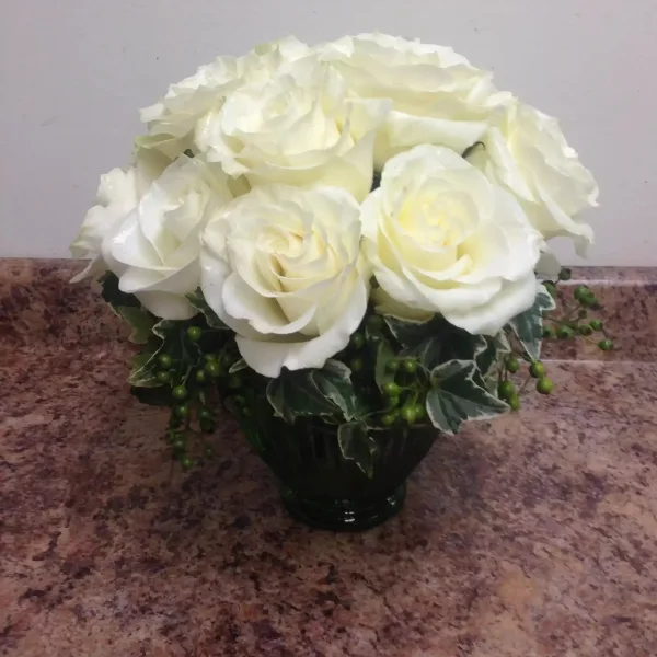 White rose bouquet in a dark vase with variegated greenery