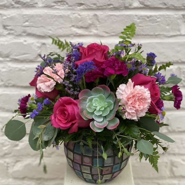 Pink roses and carnations in a mosaic vase with a succulent accent