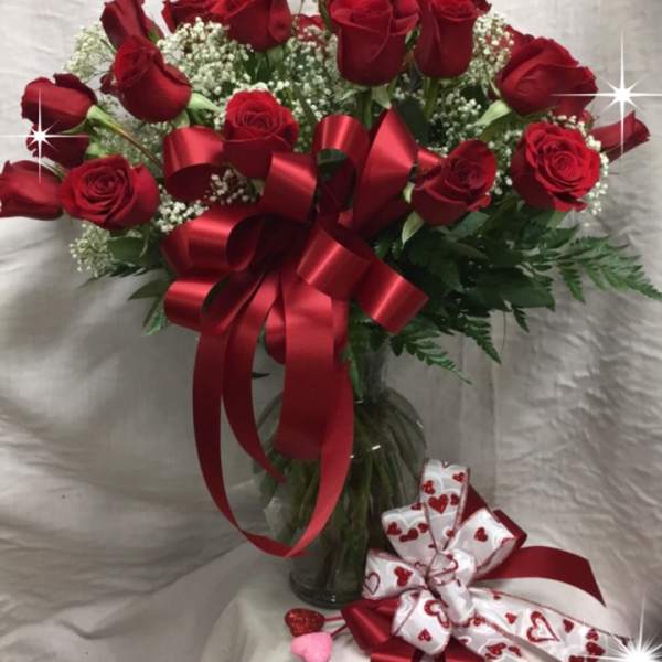 Bouquet of red roses with a red ribbon in a glass vase