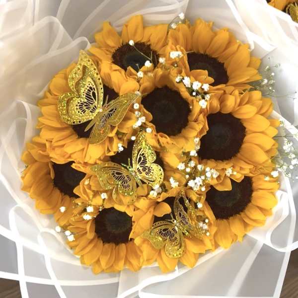 Bouquet of sunflowers wrapped in white paper with gold butterfly accents