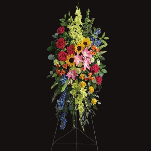 Tall standing floral spray with roses, lilies, sunflowers, and blue accents