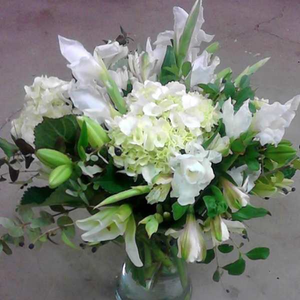 White lilies and hydrangeas arranged in a clear glass vase