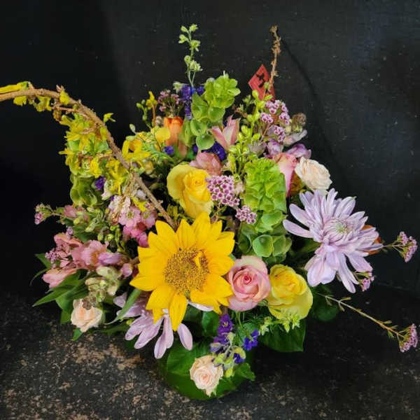 Colorful mixed flower arrangement with sunflowers, roses, and purple daisies