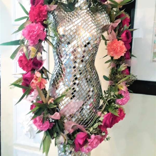 Pink and coral floral garland wrapped around a mirrored mannequin form