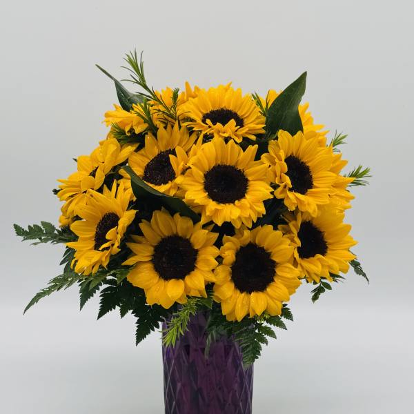 Bouquet of yellow sunflowers in a purple vase