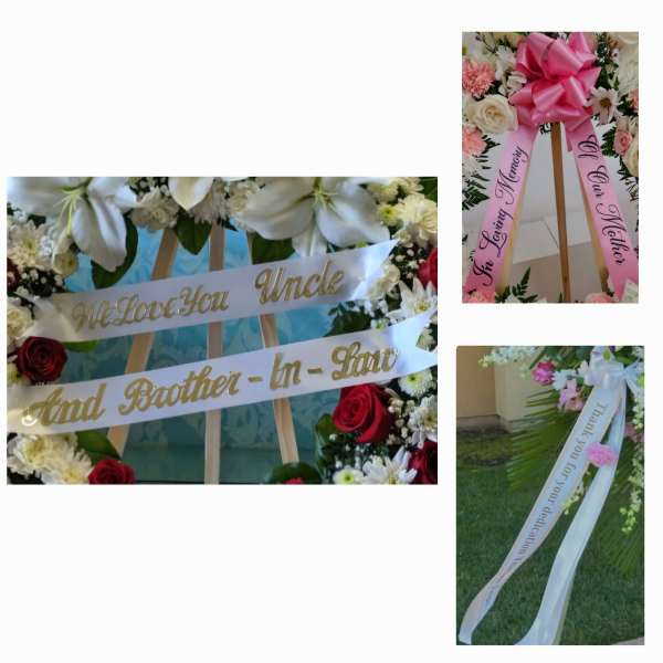 Floral funeral wreaths with pink and white ribbons on easels
