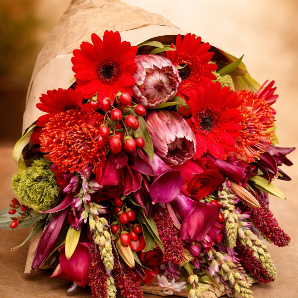 Bouquet of red and pink flowers wrapped in brown paper