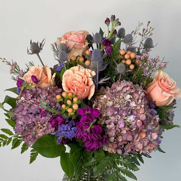 Bouquet of peach roses and purple hydrangeas in a glass vase