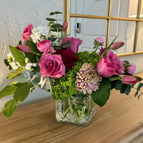 Pink roses and mixed blooms arranged in a clear glass vase