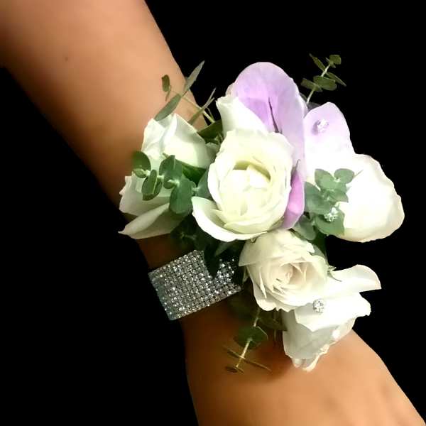 White rose wrist corsage with light lavender accents on a rhinestone band.