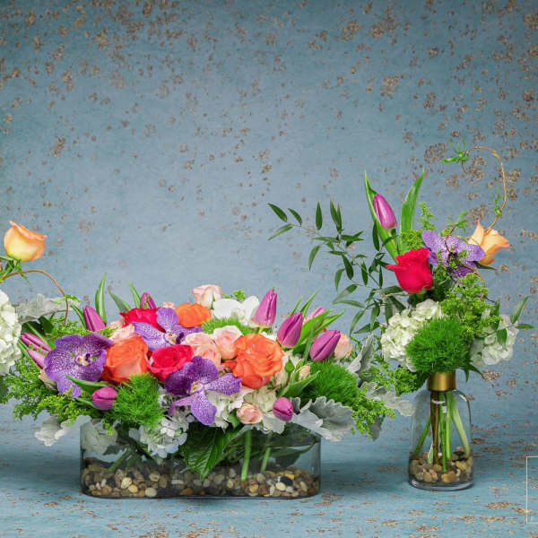 Three colorful floral arrangements in glass vases and a low rectangular container