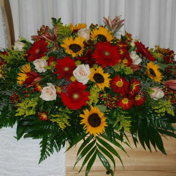Large casket spray with red and yellow flowers and white roses