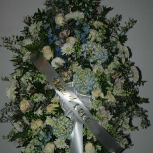 Large standing floral wreath with white and blue flowers and a satin ribbon