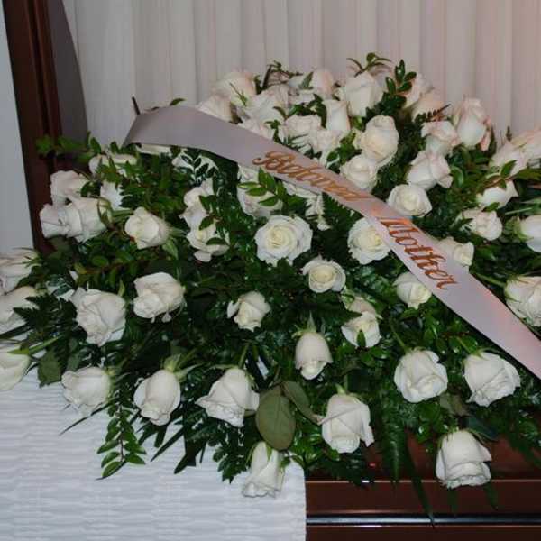 Large white rose funeral spray with a memorial ribbon
