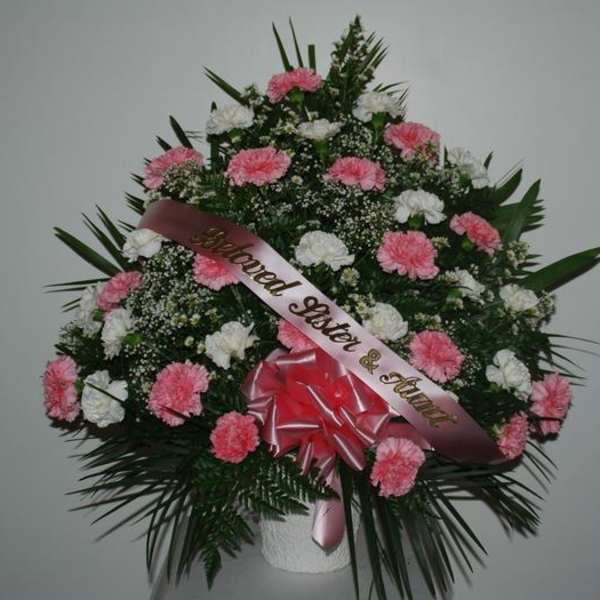 Pink and white carnation funeral spray with a memorial ribbon