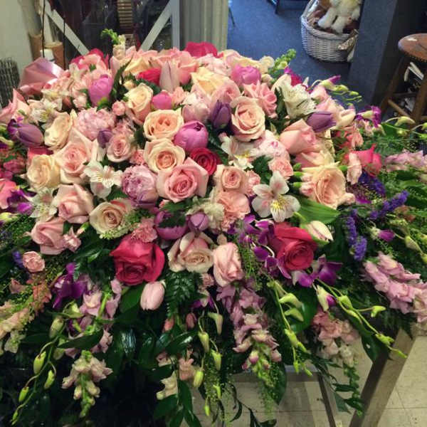 Large pink and purple floral arrangement with roses and orchids