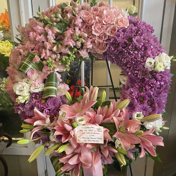 Large pink and purple funeral wreath with lilies and roses on an easel