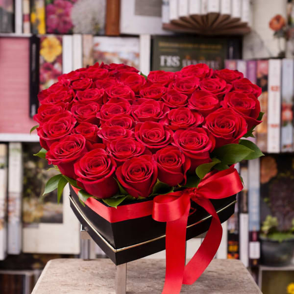 Heart-shaped bouquet of red roses in a black box with a red ribbon