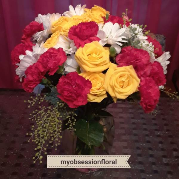 Bouquet of yellow roses, red carnations, and white daisies in a vase