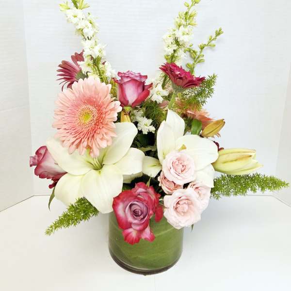 Mixed bouquet in a green glass vase with pink, white, and burgundy flowers