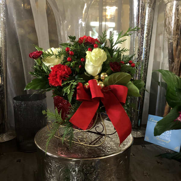 Red and white floral arrangement with a large red bow in a decorative vase
