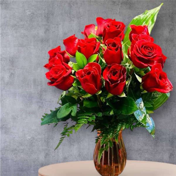 Red roses arranged in an amber glass vase with green foliage