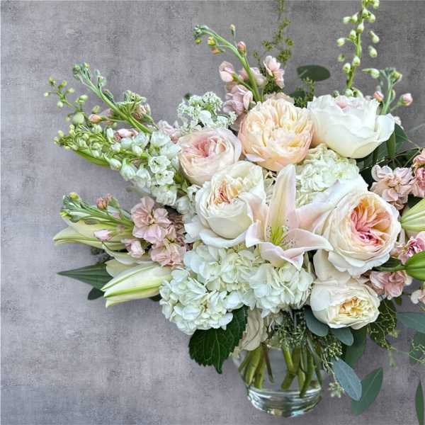 Blush and white bouquet with roses, lilies, and hydrangeas in a glass vase
