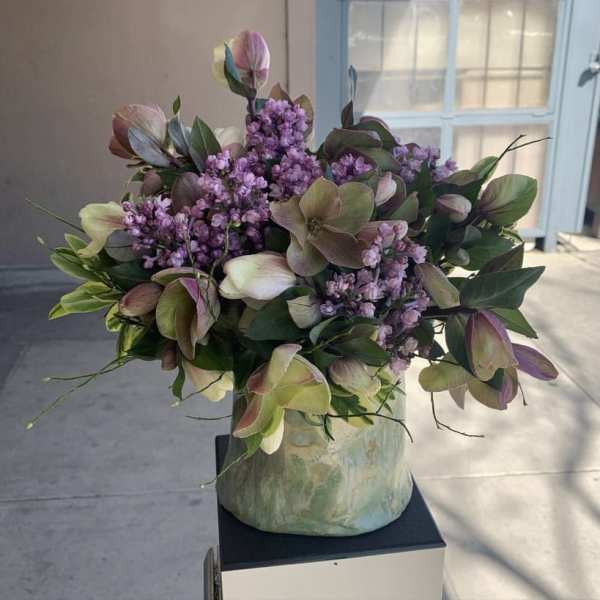 Bouquet of purple flowers and green foliage in a ceramic vase