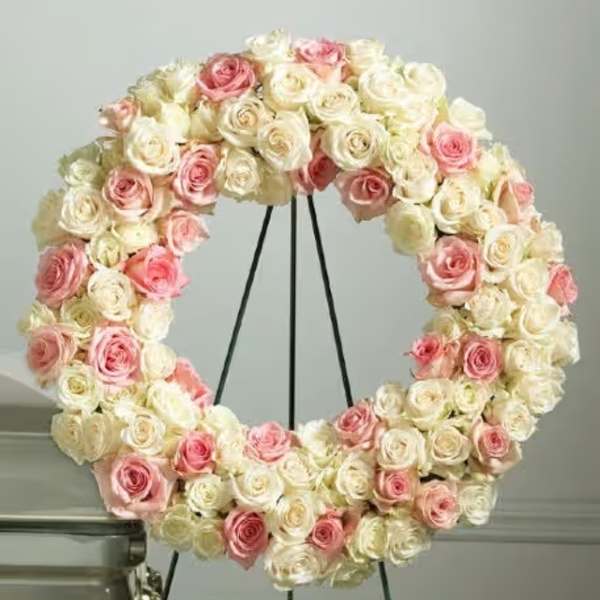 Circular wreath of pink and white roses on a black stand