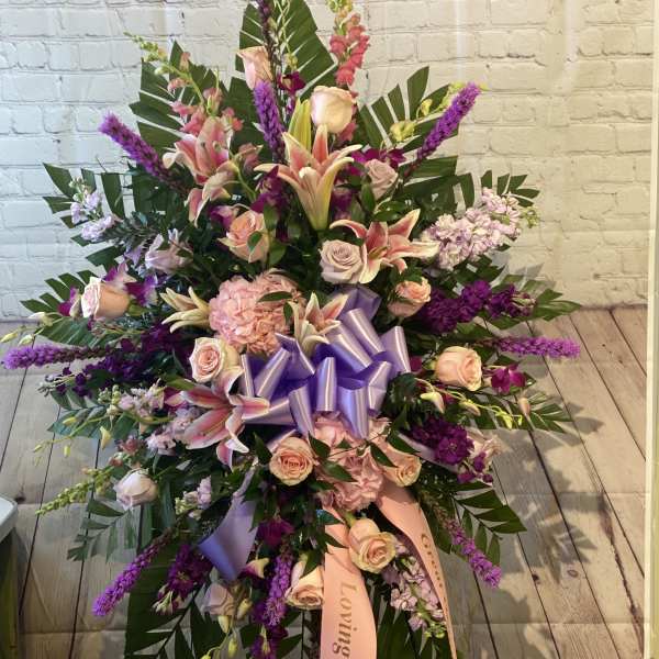 Large standing floral spray with pink lilies, roses, and purple accents
