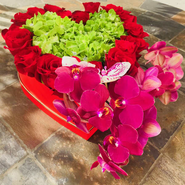 Heart-shaped arrangement of red roses and pink orchids with green hydrangeas