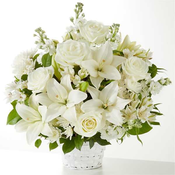 White roses and lilies arranged in a white basket.