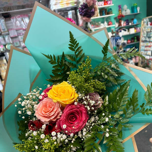 Bouquet of multicolored roses wrapped in turquoise paper