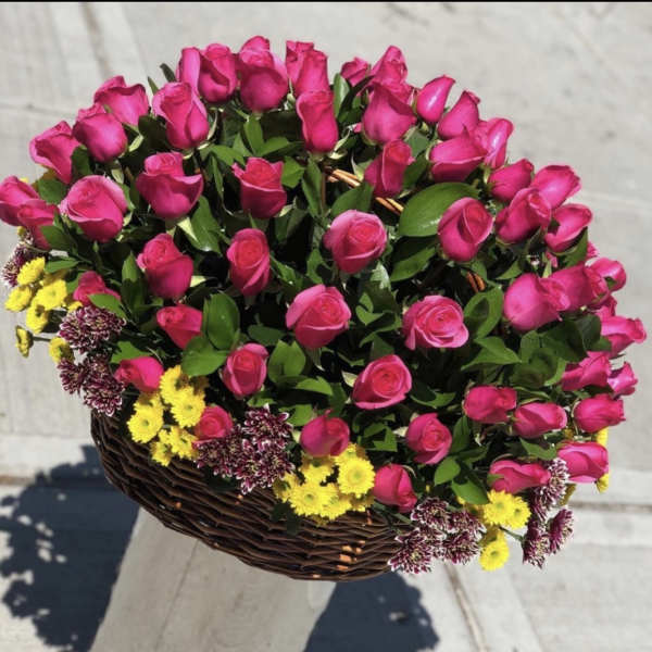 Basket of pink roses with small yellow and purple flowers