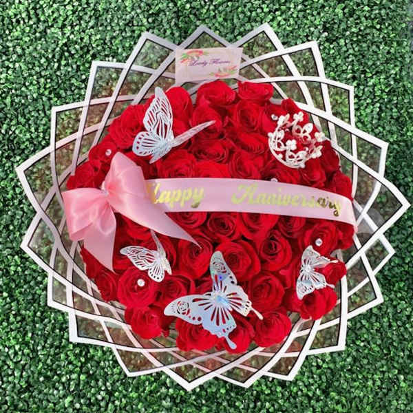 Round bouquet of red roses with pink ribbon and butterfly decorations