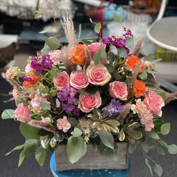 Mixed pink and orange flower arrangement in a wooden box