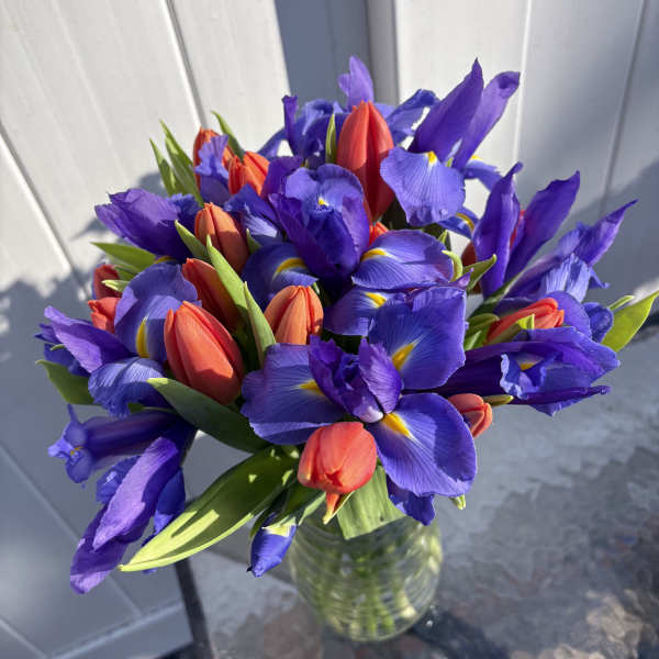 Bouquet of purple irises and red tulips in a glass vase