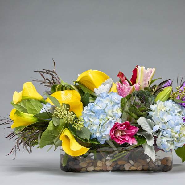 Colorful mixed flower arrangement in a low glass vase