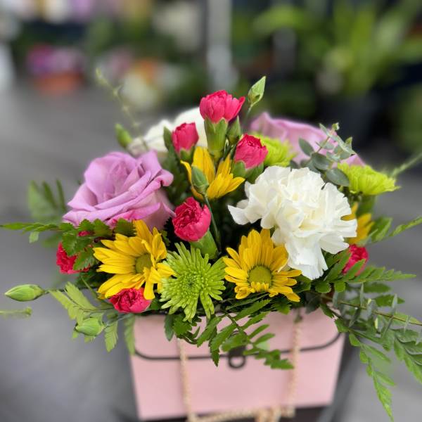 Mixed bouquet in a pink gift box with roses, carnations, and daisies