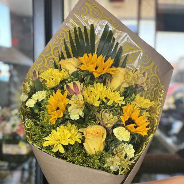Yellow mixed bouquet wrapped in brown paper with a ribbon