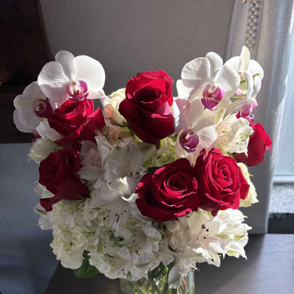 Red roses and white orchids in a clear glass vase
