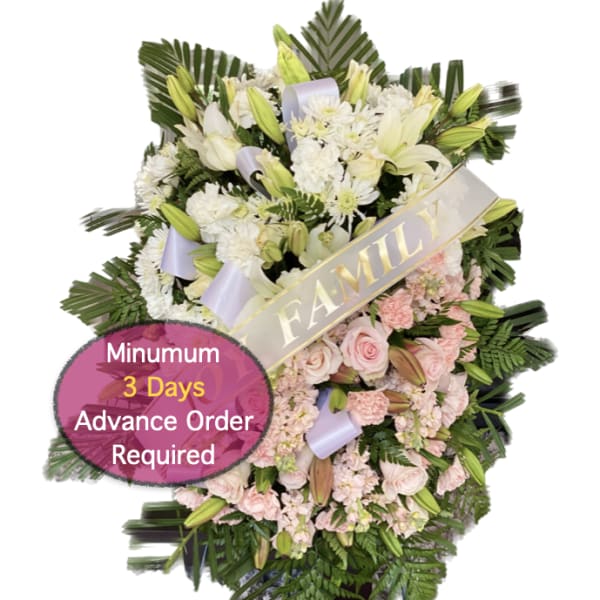 Standing funeral spray with white lilies, pink roses, and a family ribbon