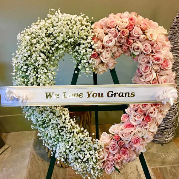 Heart-shaped floral tribute with pink roses and white baby's breath