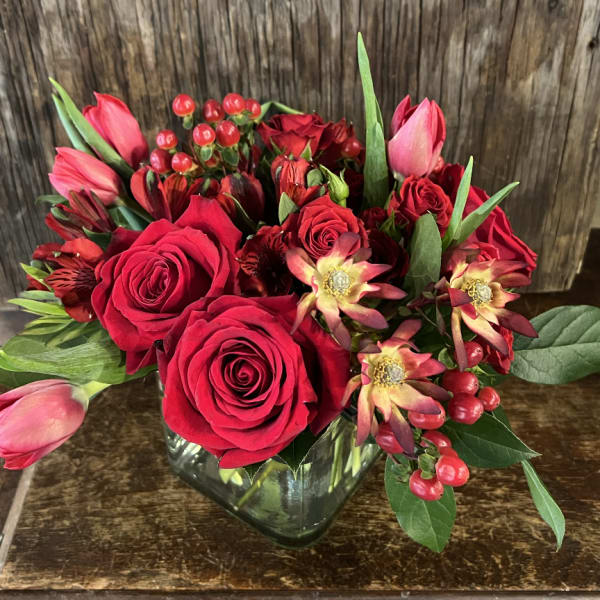 Red roses and pink tulips arranged in a glass vase