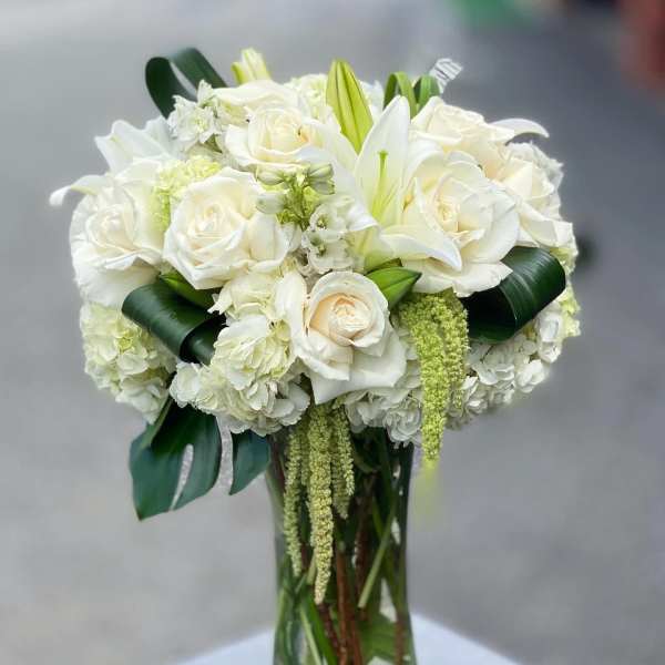 White roses and lilies arranged in a clear glass vase